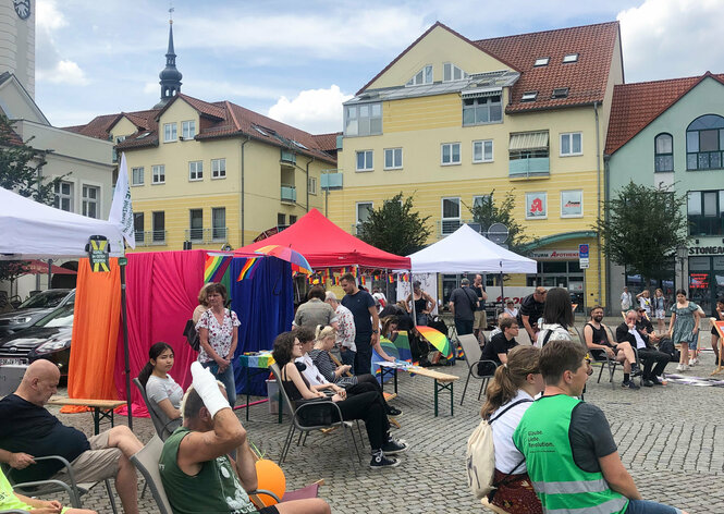 Menschen und Sonnenschirme und Regenbogenfahnen auf dem Marktplatz von Spremberg