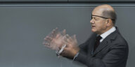 Olaf Scholz mit auslandender Gestik und Augenklappe im Bundestag