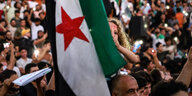 Eine Menschenmenge protestiert mit Fahnen der syrischen Opposition