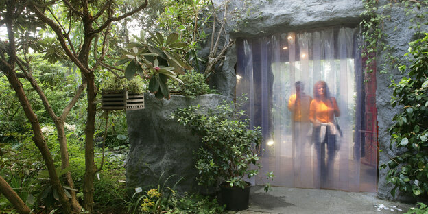 Menschen betreten ein Tropenhaus durch einen halbdurchsichten Plastikvorhang