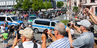 Menschen zwischen Polizeiwagen und Traktoren auf einem öffentlichen Platz