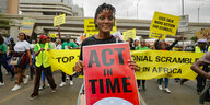 Die Aktivistin Vanessa Nakate hält während einer Protestaktion ein Plakat in die Kamera: Act in time.