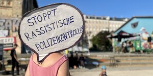 Frau im Görlitzer Park hält Schild: "Stoppt rassistische Polizeigewalt"