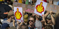 Menschen mit Protestschildern, die auf das Logo des weltweit größten Mineralöl- und Erdgasunternehmen Shell anspielen