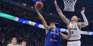 Serbiens Guard Bogdan Bogdanovic wirft neben Deutschlands Forward Daniel Theis