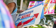 Eine Demonstrantin hält ein Schild mit der Aufschrift „Rassismus ist Keine Alternative für Deutschland“ in den Händen