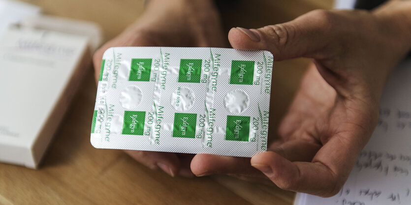 Tabletten in einer Hand auf einem Schreibtisch.