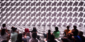 Eine Installation zeigt grafische Wellen, davor Publikum