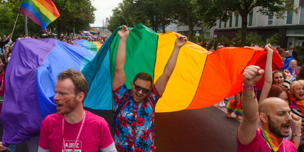 Menschen mit Regenbogenfahne bei einer Demonstration.