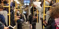 In einer vollen U-Bahn schauen Menschen auf Handys und in Zeitungen