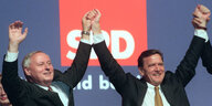 Die Politiker Lafontain und Schröder reißen die Arme hoch.