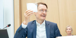 Lauterbach mit einer verpackten FFP-2-Maske in der Hand