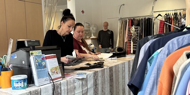 Zwei Frauen stehen in einem Laden mit Kleidung hinter dem Ladentisch