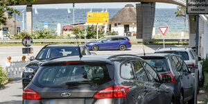 Parkende Autos am Straßenrand, im Hintergrund die Ostsee
