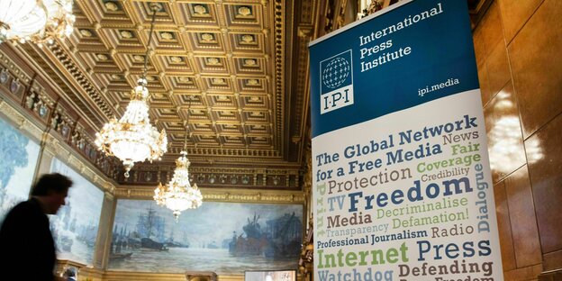 Ein Banner des International Press Instituts hängt bei einer Veranstaltung in einem festlich geschmückten Raum