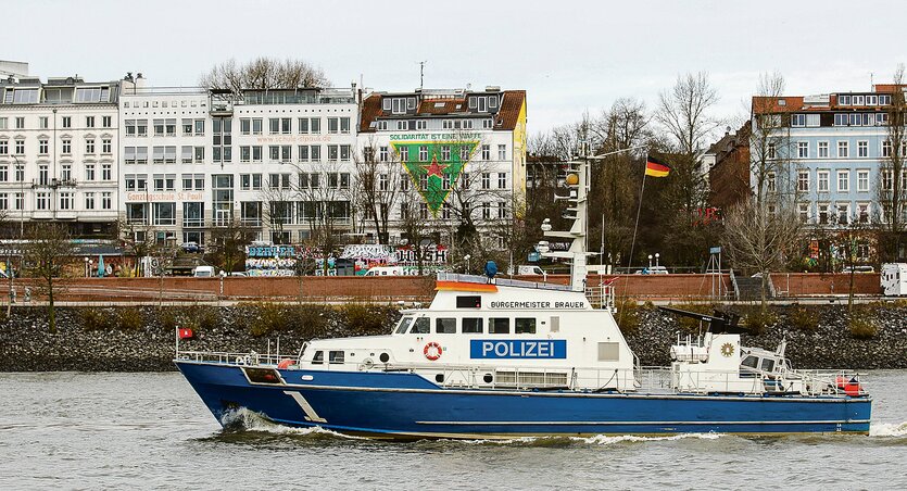 Ein Polizeischiff fährt vor der Hafenstraße über die Elbe.