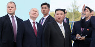 Wladimir Putin und Kim Jong Un schauen umringt von Männern nach oben