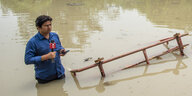 Journalist im Hochwasser stehend