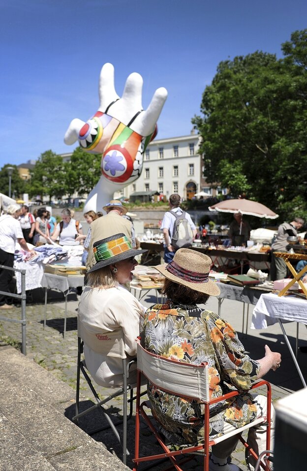 Nana-Figur von Niki de Saint Phalle, im Vordergrund sind Flohmarktstände zu sehen
