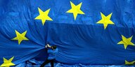 Ein Mann steht vor einer riesigen Europa-Fahne