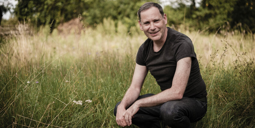 Daniel Rapoport hockt in einem Garten