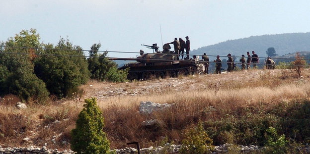 Panzer und Soldaten in Landschaft.