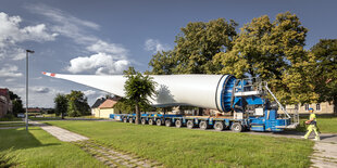 Ein Mann steht vor einem Schwertransporter mit Rotorblatt für Windrad