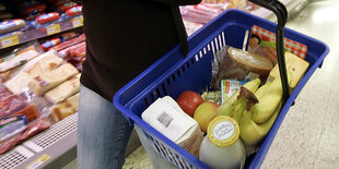 Mensch mit Einkaufskorb im Supermarkt.