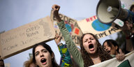 2 junge Frauen mit aufgerissenen Mündern und ein Megafon in einer Demonstrationsreihe