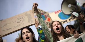 2 junge Frauen mit aufgerissenen Mündern und ein Megafon in einer Demonstrationsreihe