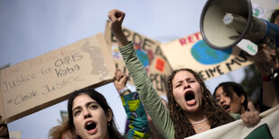 2 junge Frauen mit aufgerissenen Mündern und ein Megafon in einer Demonstrationsreihe