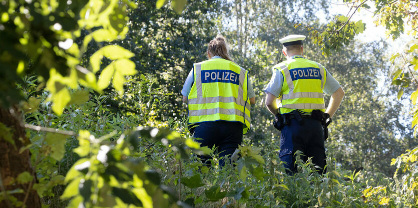 Polizisten sichern einen Tatort nahe eines Bahndamms nach Kabelbränden