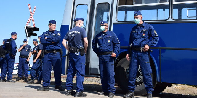 Ungarische Polizsten in Röszke vor einem Bus