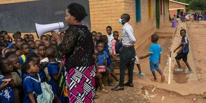 Grundschüler in Malawi, ihre Lehrerin erklärt etwas durchs Megafon