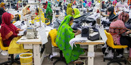 In einer Fabrikhalle in Bangaldesch sitzen Dutzende Näherinnen an Nähmaschinen