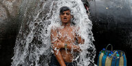 Über einen jungen Mann strömt Wasser aus einem Riss in einer Trinkwasserpeiplein 2019 in Kalkutta, Indien