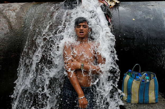 Über einen jungen Mann strömt Wasser aus einem Riss in einer Trinkwasserpeiplein 2019 in Kalkutta, Indien