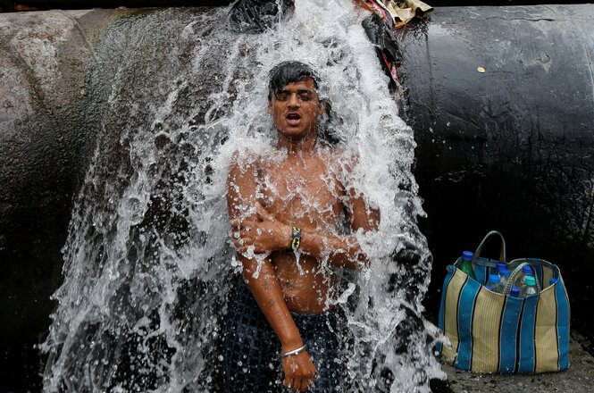 Über einen jungen Mann strömt Wasser aus einem Riss in einer Trinkwasserpeiplein 2019 in Kalkutta, Indien