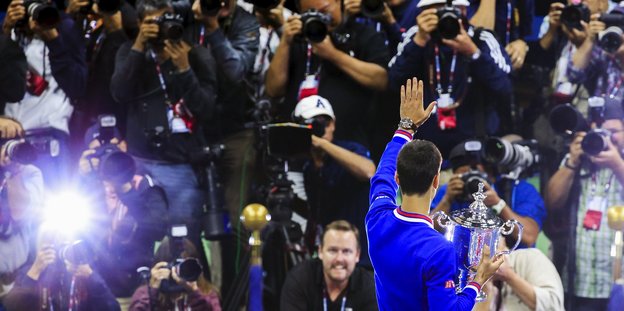 Repoter machen Fotos von Novak Djokovic, den man von hinten sieht