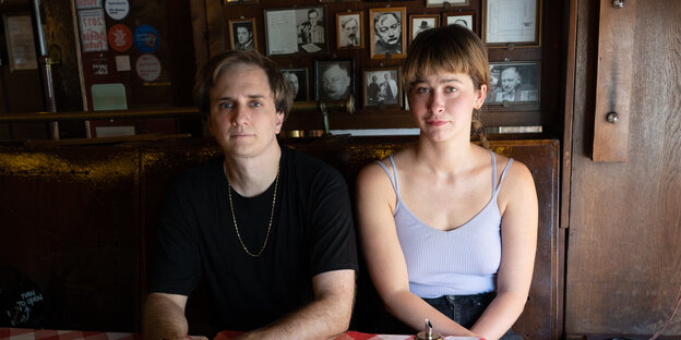Ein Mann und eine Frau sitzen in einem Restaurant vor einer Wand mit Fotos