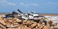 Am Strand in Darna türmen sich auf dem Sandstrand Trümmer auf zerbeulte Autos