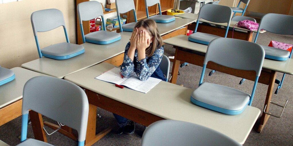 Kund sitzt alleine im Klassenzimmer.