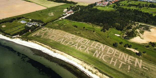 Luftbild mit Feld an der Küste, auf dem groß steht "Daniel, wir wollen deinen Nationalpark nicht"