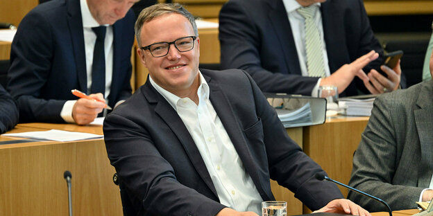 Mario Voigt (CDU), Fraktionsvorsitzender, sitzt im Plenarsaal des Thüringer Landtag und grinst zufrieden