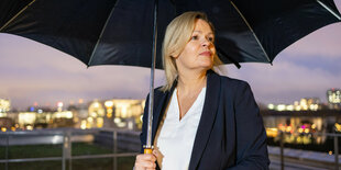 Nancy Faeser mit Regenschirm auf einem Dach