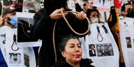 Eine Frau lässt sich bei einem Protest eine symbolishe Schlinge um den Hals legen