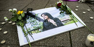 Ein Bild der verstorbenen Iranerin Mahsa Amini liegt auf dem Boden mit Blumen und Kerzen