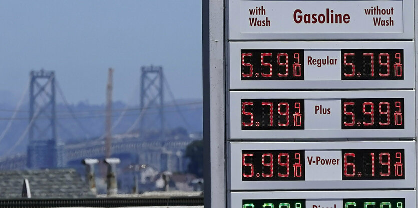 Die Die San Francisco-Oakland Bay Bridge erhebt hinter einer Preistafel einer Tankstelle in San Francisco