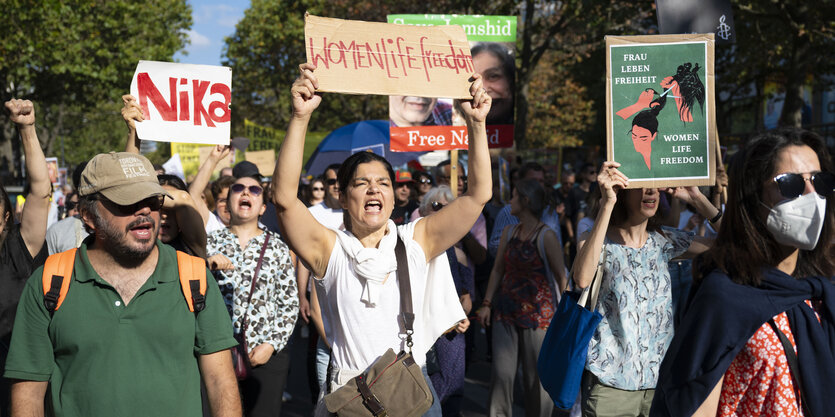 Demonstration auf dem Kurfürstendamm zum ersten Todestag von Jina Mahsa Amini, Menschen halten Schilder hoch