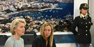 Ursula von der Leyen sitzt neben Giorgia Meloni, an der Wand hängt ein Foto vom malerischen Hafen in Lampedusa